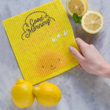 Yellow Swedish dishcloth with 'Good Morning' text and lemon slices on a gray surface