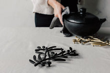 Person holding a black pot with decorative elements on a light background