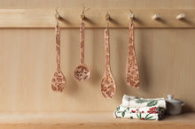 Decorative spoons hanging on a wooden wall with a floral-patterned box below.