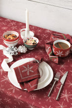 Dining table setting with red tablecloth, white plates, and festive decor.
