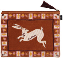 Velvet pouch with a hopping rabbit design on a rust background with geometric border
