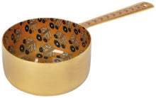 Gold measuring cup with black leaf pattern on a white background